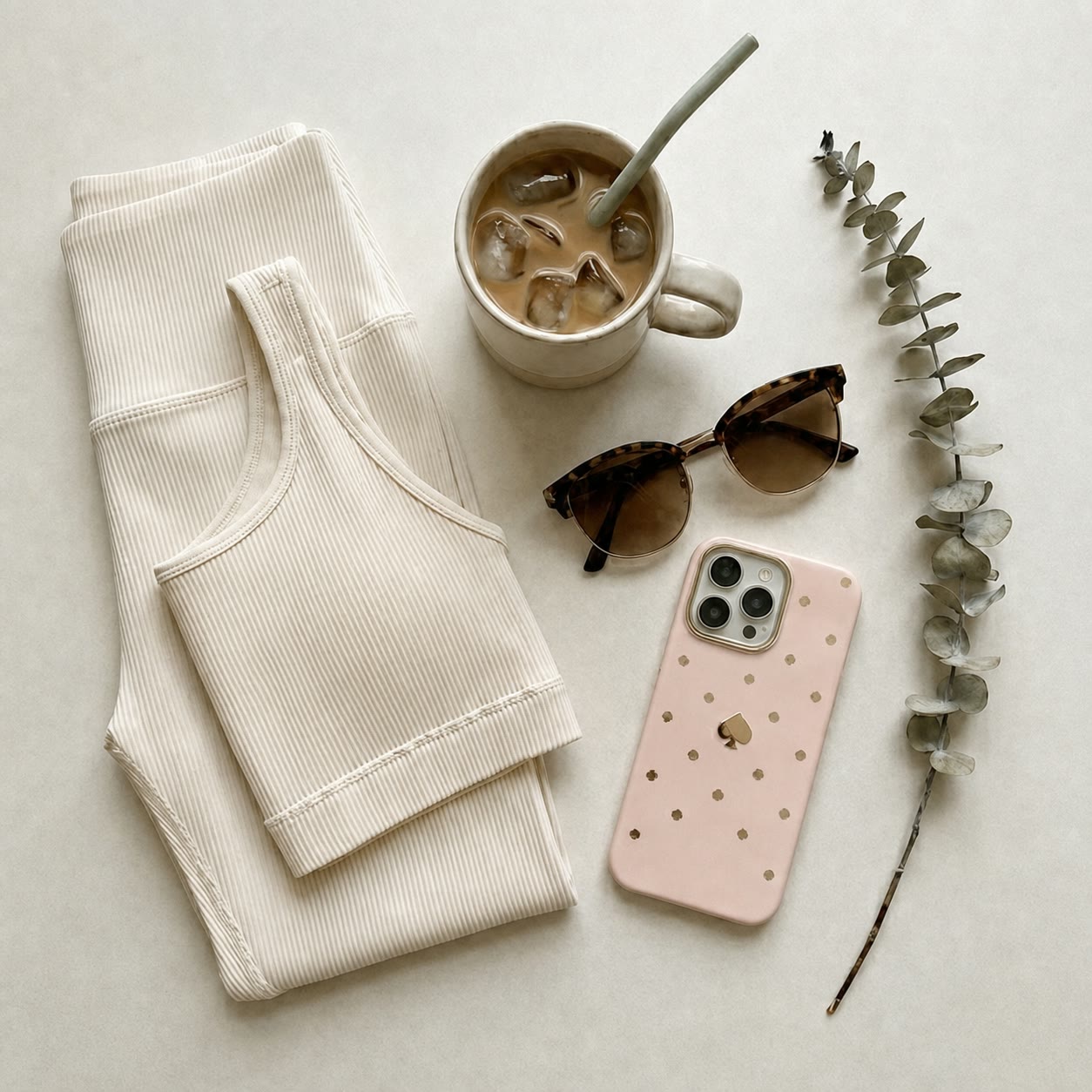 Coffee, a laptop, and everyday essentials arranged on a warm neutral surface